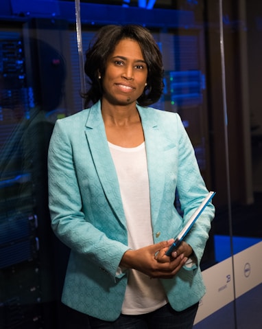 woman in blue blazer standing beside glass wall