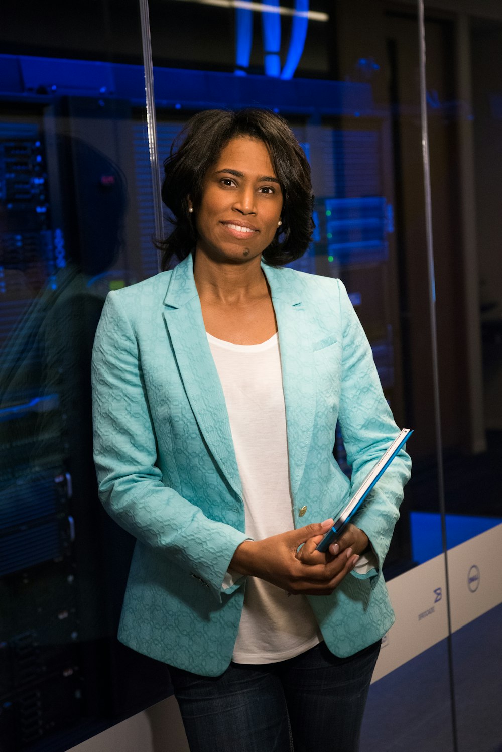 woman in blue blazer standing beside glass wall