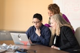 three women beside table looking at MacBook