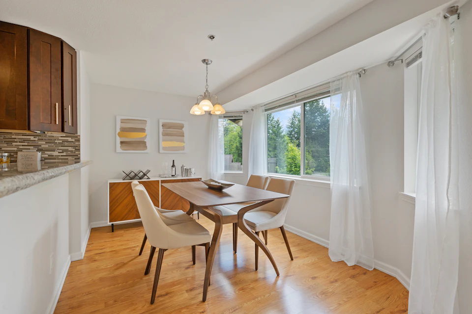 Large wooden table surrounded by six chairs in a modern, well-lit dining room setting