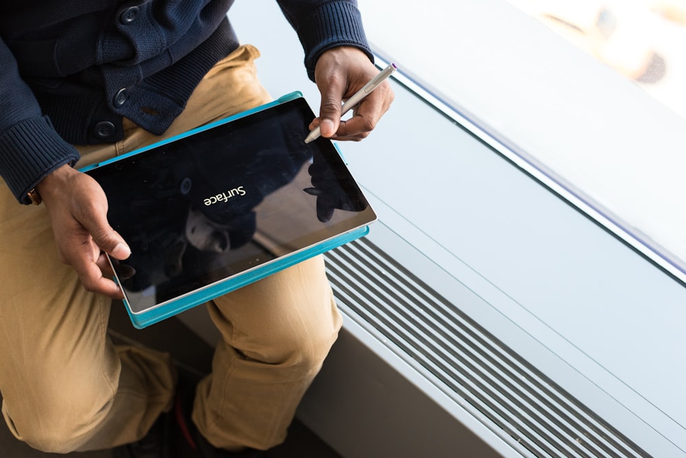 person holding tablet computer using pen