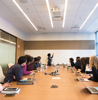 people on conference table looking at talking woman