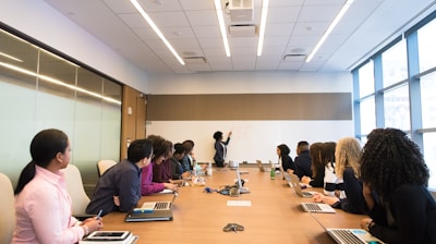 people on conference table looking at talking woman