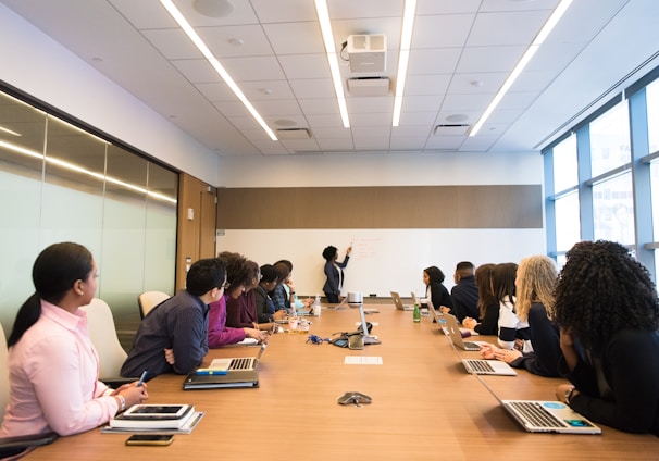 people on conference table looking at talking woman