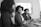 grayscale photography of two women on conference table looking at talking woman