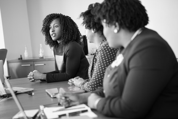Several women of colour sitting at a workplace table having a discussion.