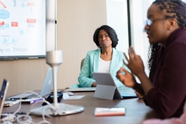 selective focus photography of woman in gray blazer looking at woman in black top