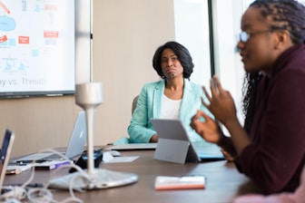 selective focus photography of woman in gray blazer looking at woman in black top