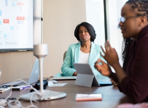 selective focus photography of woman in gray blazer looking at woman in black top