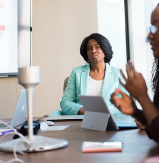 selective focus photography of woman in gray blazer looking at woman in black top