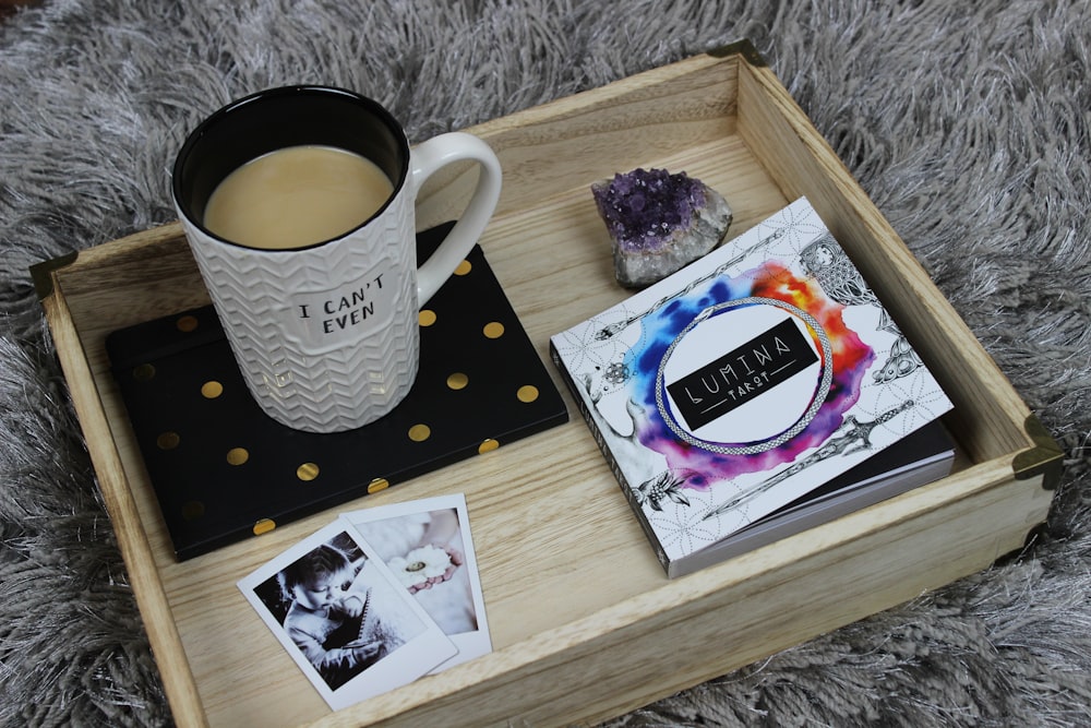 full mug beside book on brown wooden tray