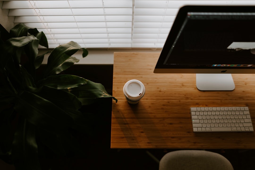 white coffee cup beside iMac