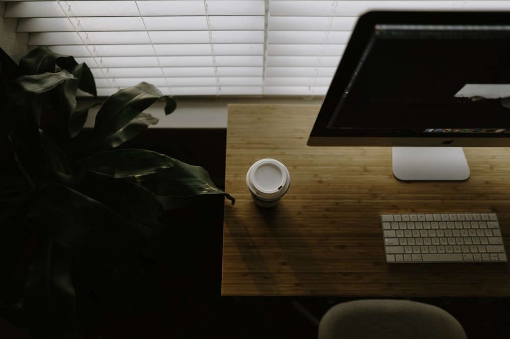 white coffee cup beside iMac