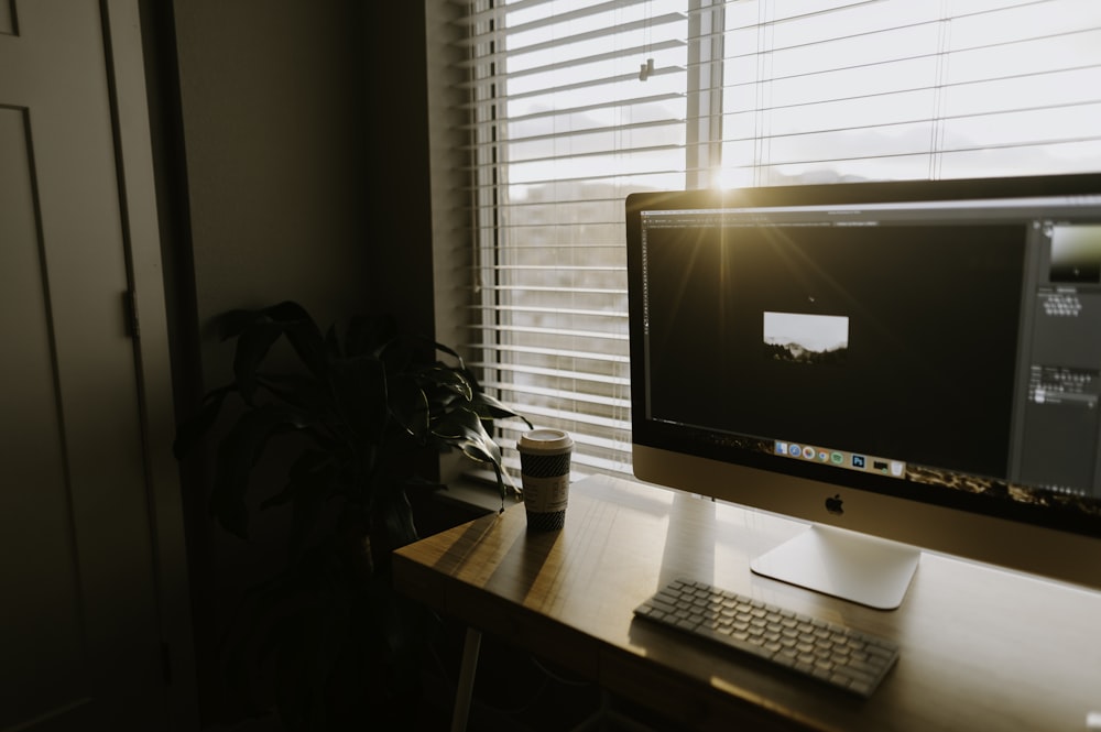 iMac argenté sur table en bois marron près de la porte fermée