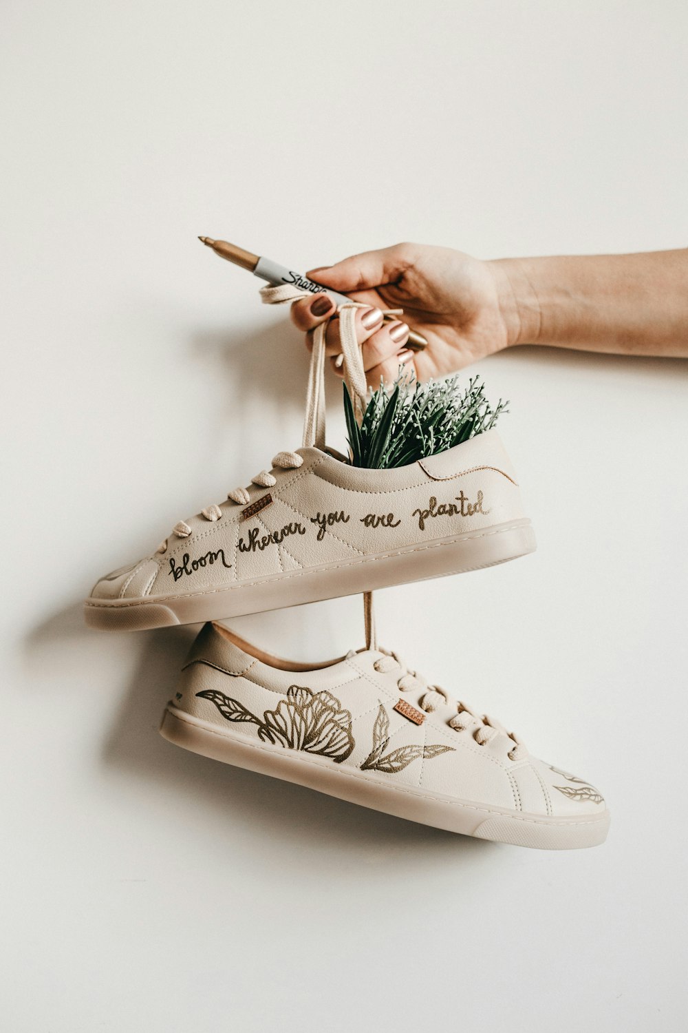 person holding pair of sneakers with flower inside