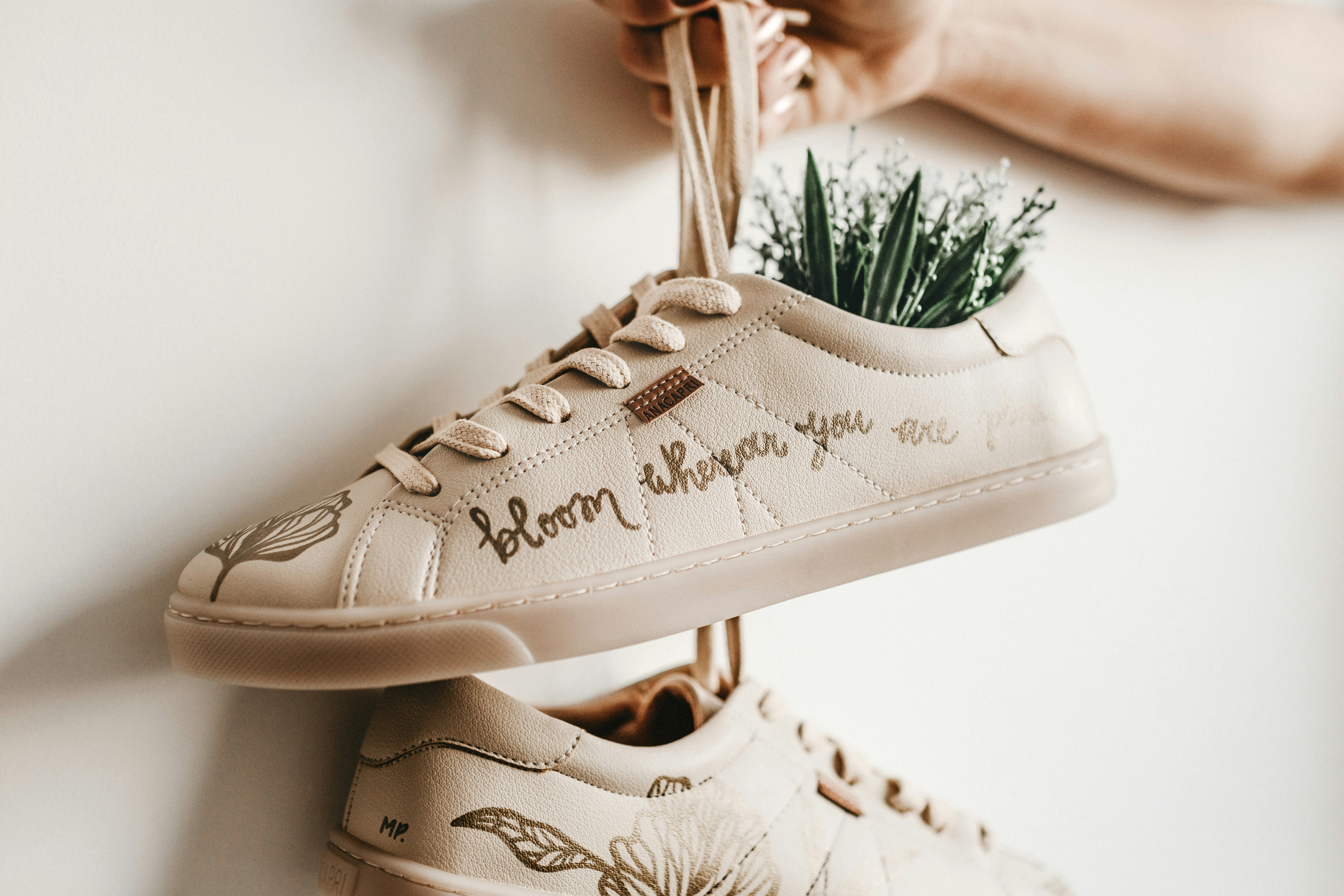 person holding white sneaker with flowers inside