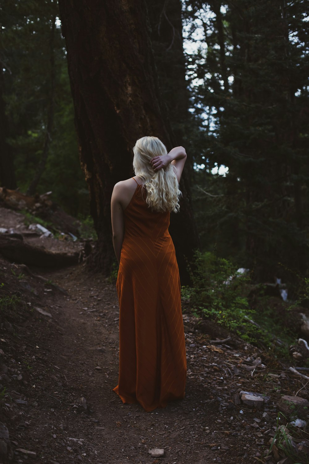 woman touching her hair near trees