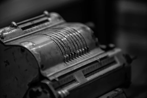 A close-up of a vintage calculator with worn keys on a wooden desk.