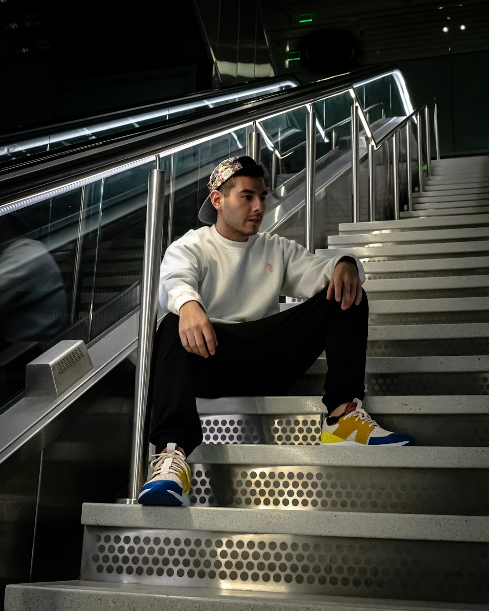 selective focus photography of man in white sweater sitting on stair