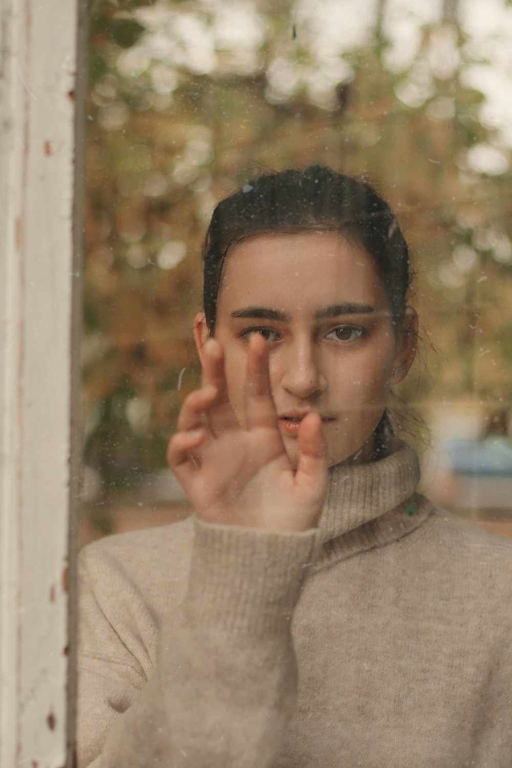 Photographie sélective de la femme debout devant une fenêtre en verre