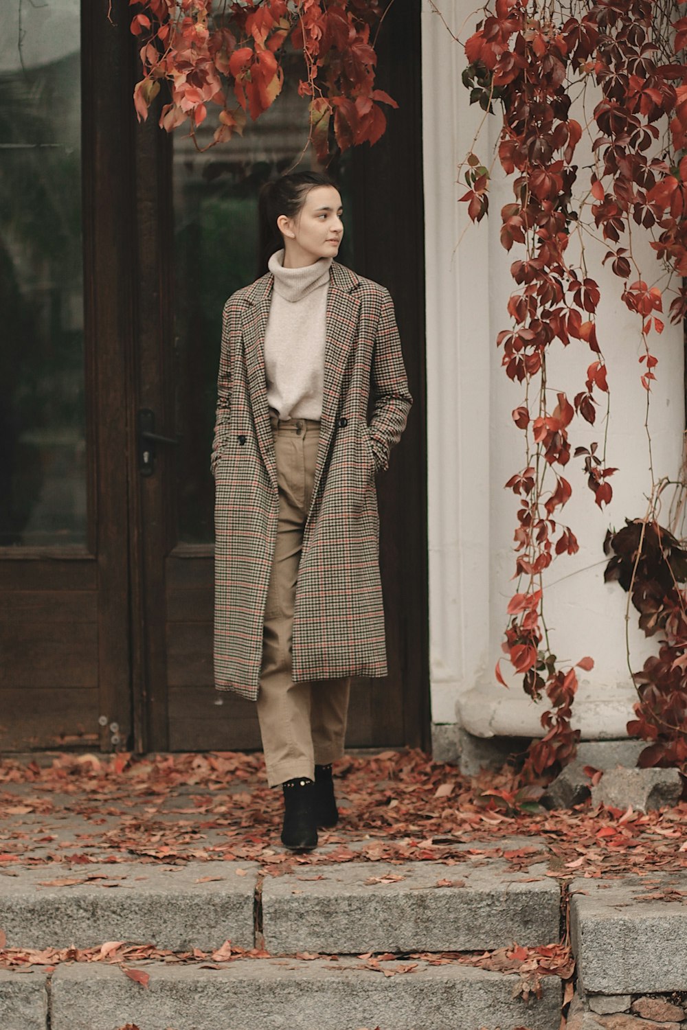 selective focus photography of standing woman in gray coat in front of door