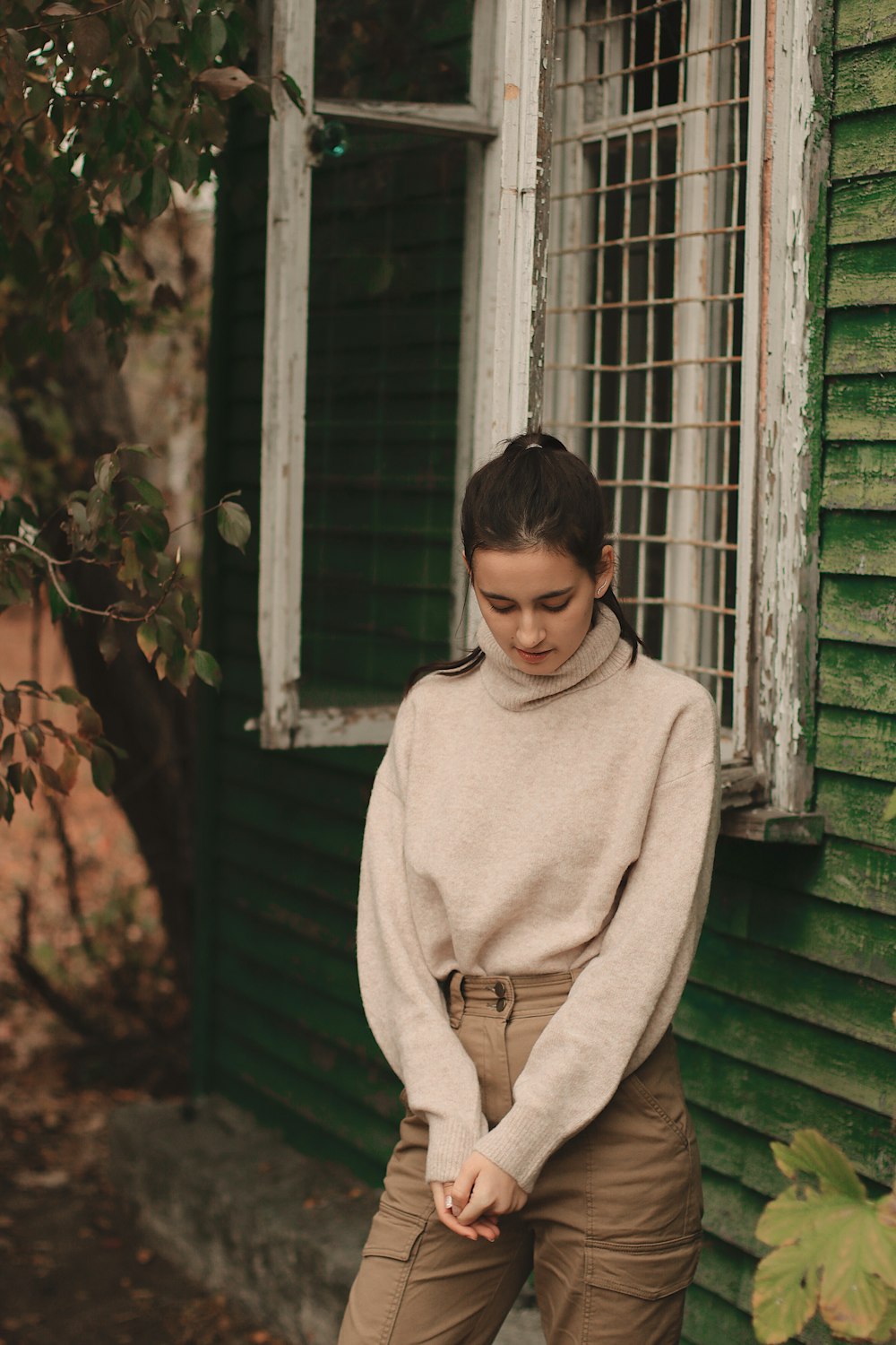 selective focus photography of woman in gray sweater standing beside window