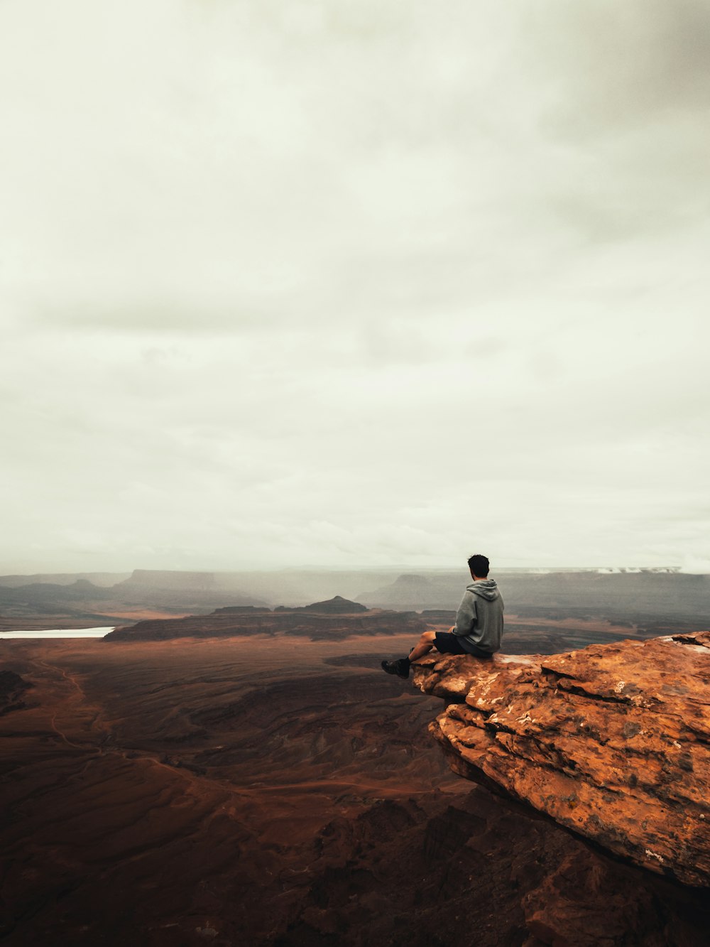 person wearing gray hoodie standing on cliff