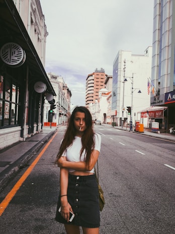 A stylish young Asian professional woman confidently using a smartphone in a modern urban setting.