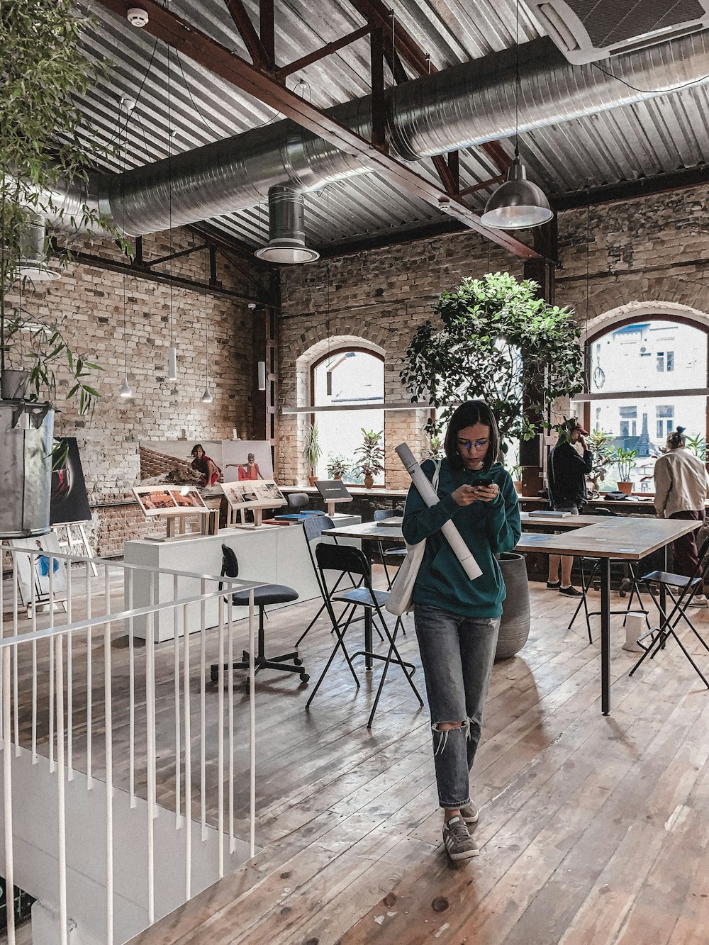 woman holding smartphone walking near table inside building