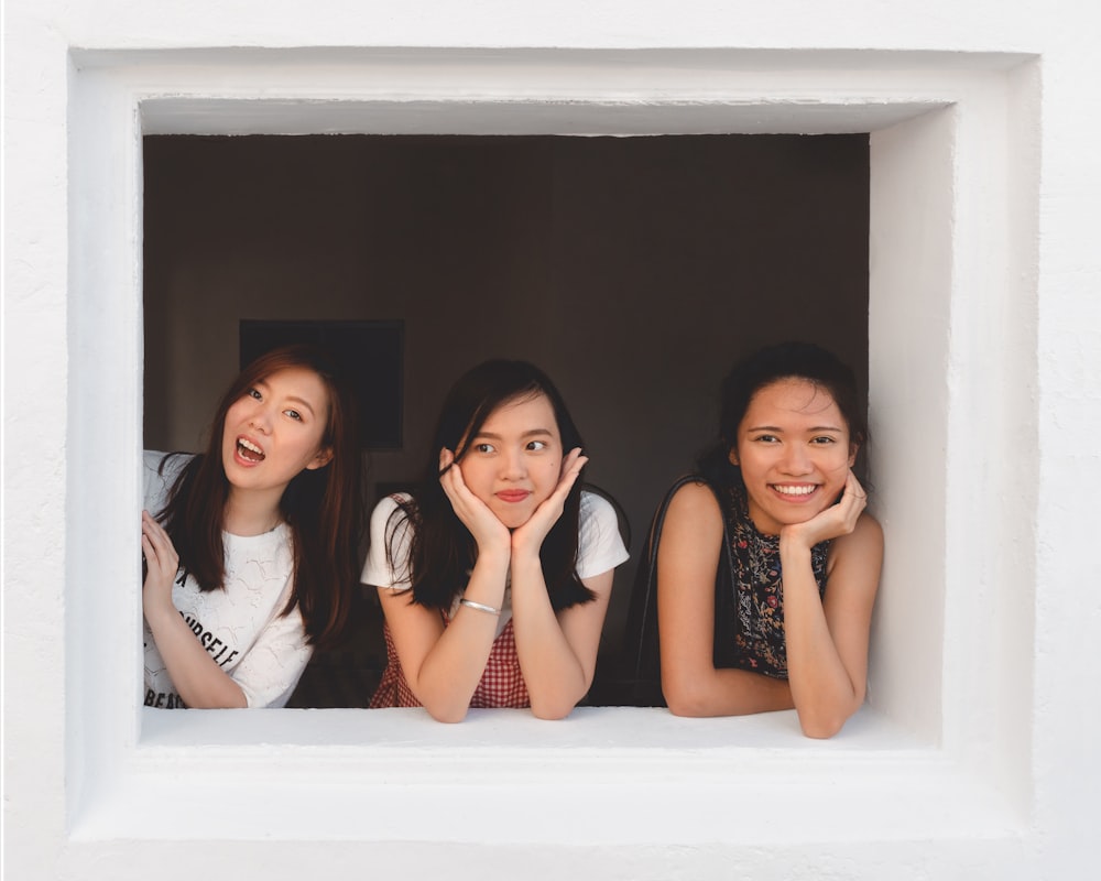 three smiling women at window