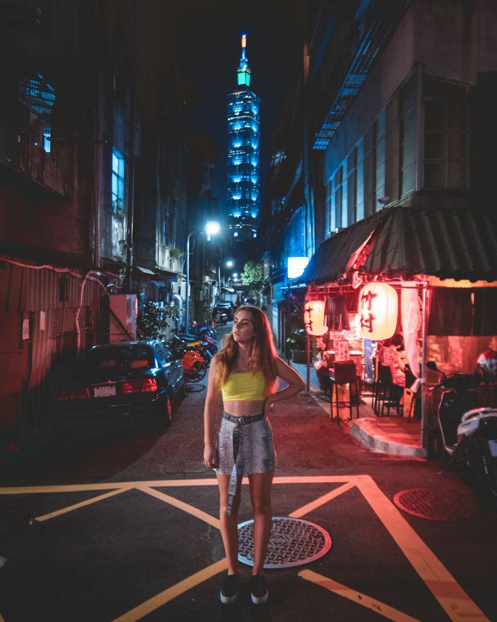 woman wearing yellow top standing on street beside buildings