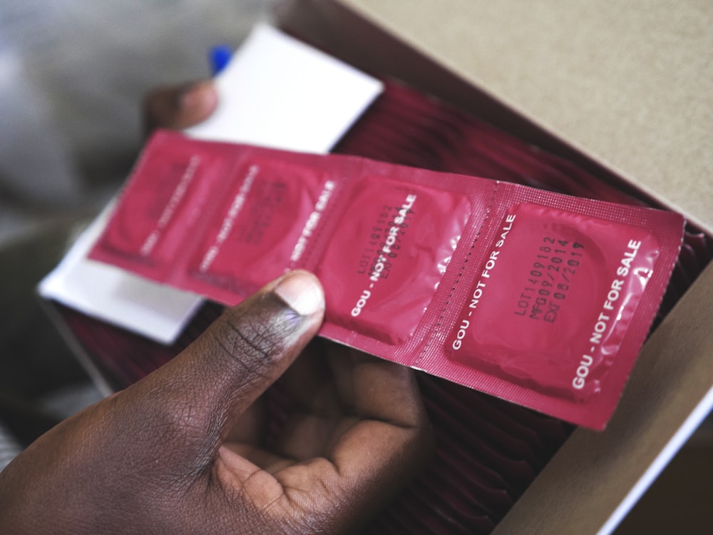man holding red condom packs