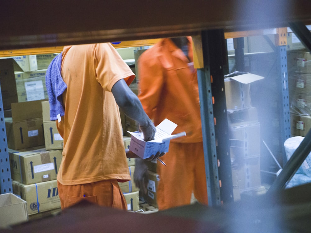 standing man in orange t-shirt holding white box