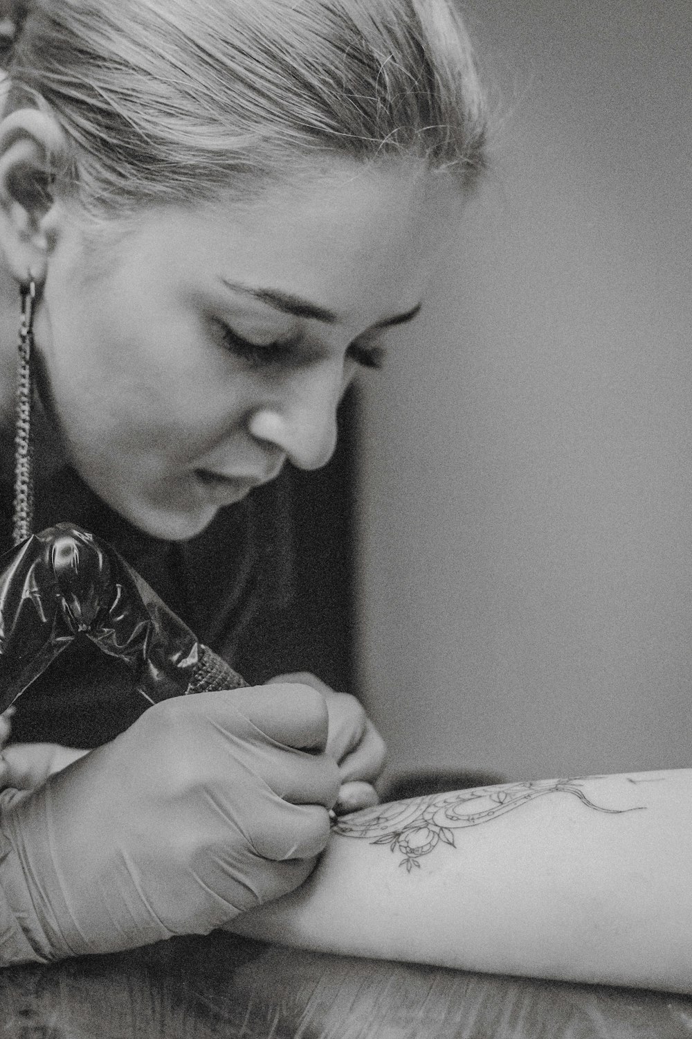 grayscale phos arm tography of woman doing tattoo on person