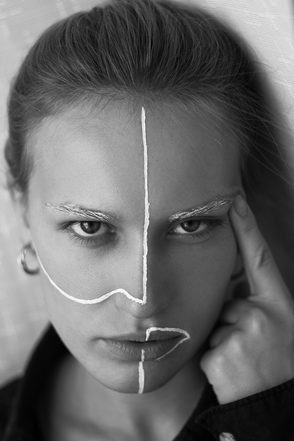 grayscale photography of woman wearing earring touching eyebrow