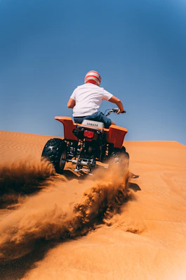 person riding ATV on desert during daytime