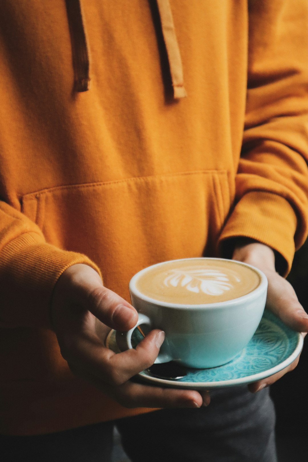 standing person holding full mug with saucer