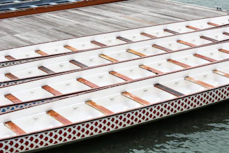 A coach giving focused training instructions to a group of eager dragon boat athletes by the riverside.