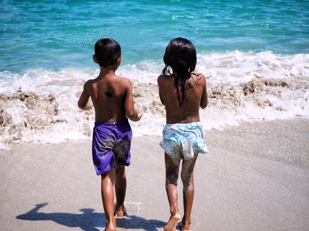 fotografia ravvicinata di due bambini in riva al mare durante il giorno