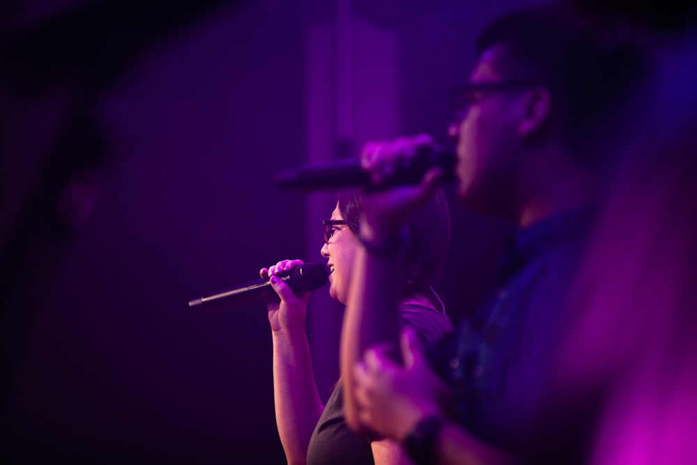 selective focus photography of woman and man singing side by side