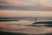 A solo traveler relaxing on a serene beach at sunset, waves gently lapping nearby.