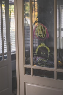 A cheerful child proudly showing a drawing to their parent in a sunny kitchen.