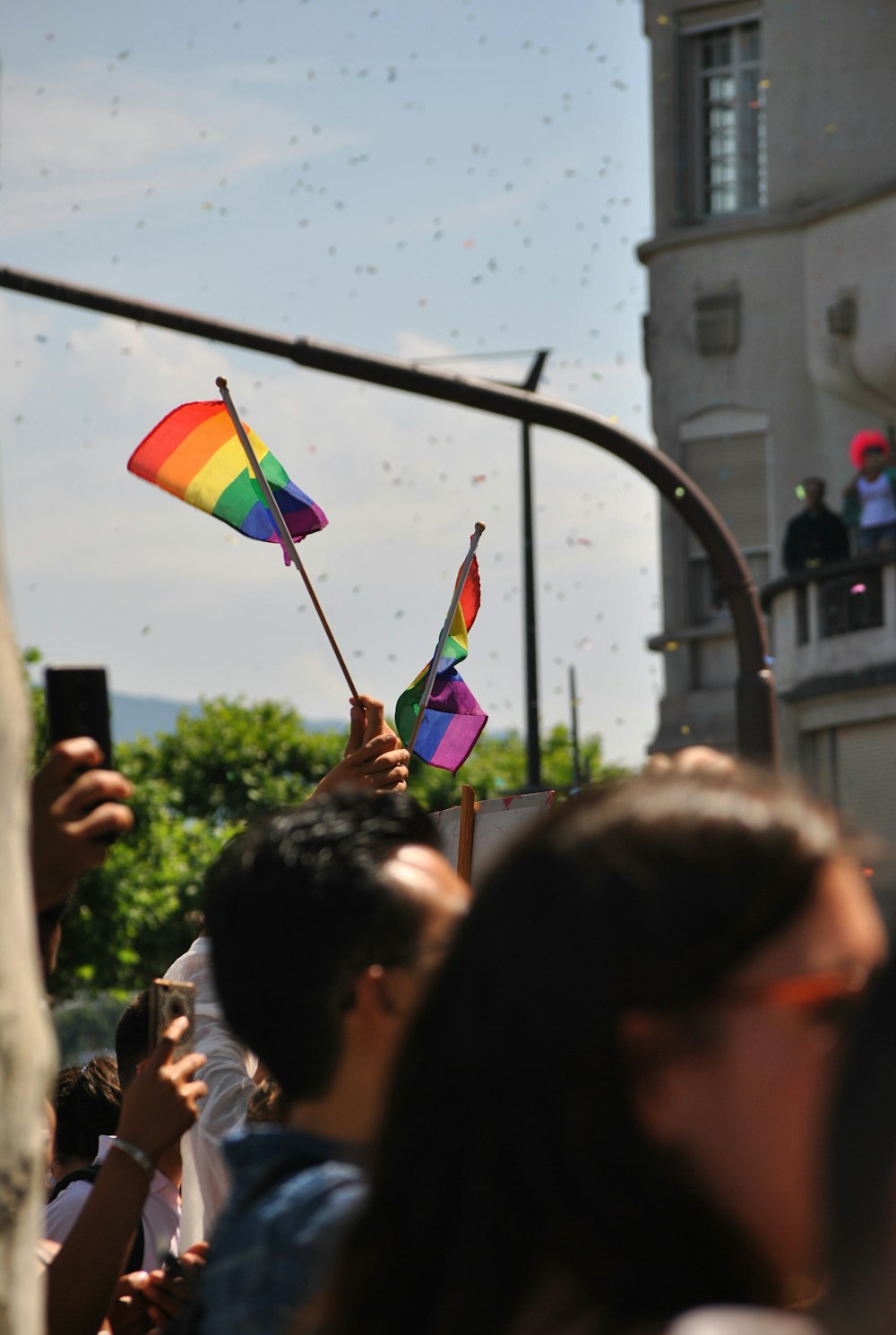 uma pessoa segurando uma bandeira do arco-íris em uma multidão