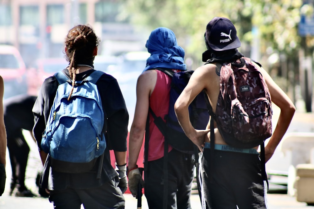 three person standing with backpacks