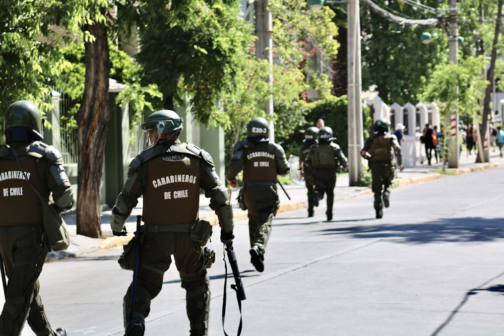 running and walking men in police uniform holding rifles during daytime