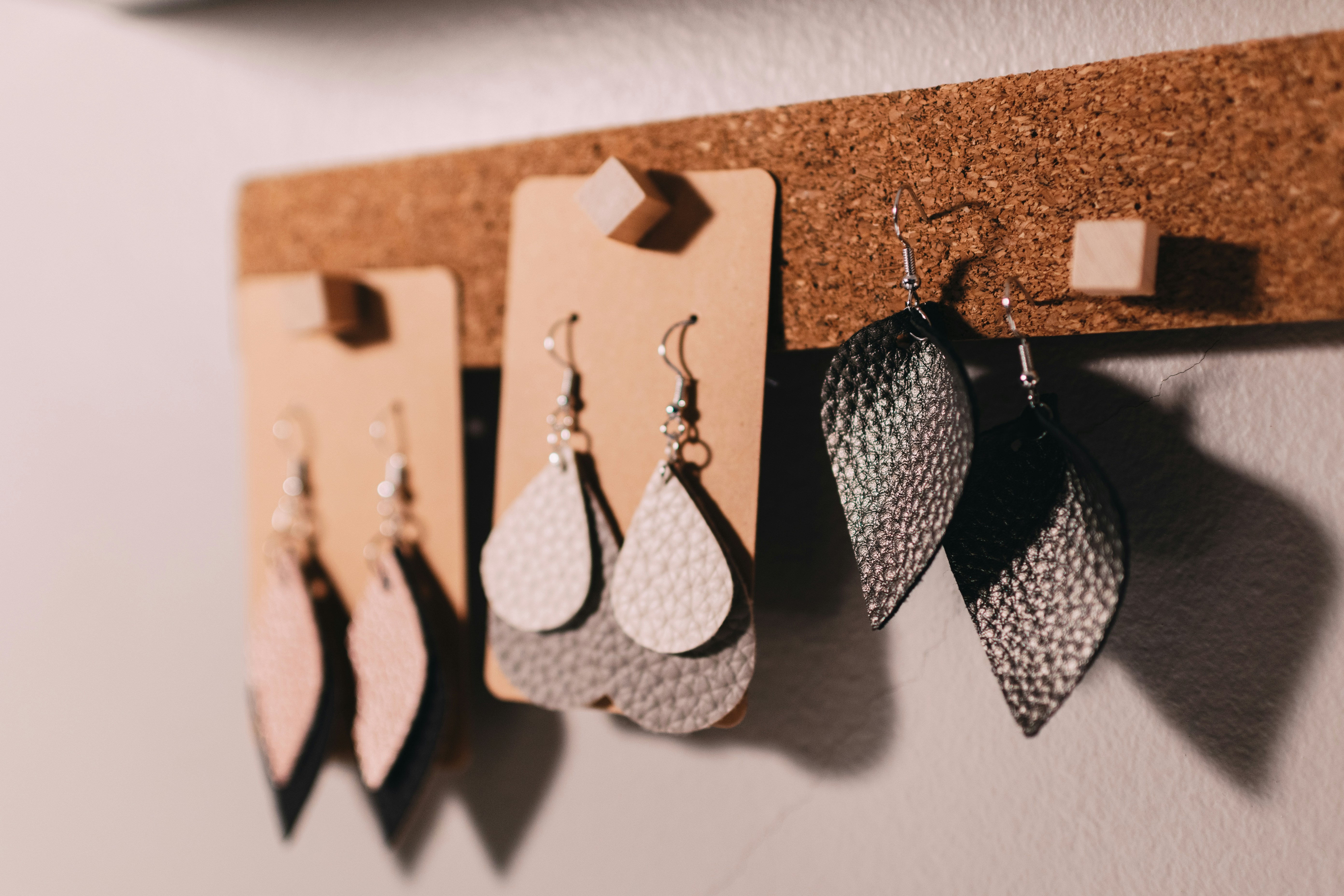 "Leather earrings hanging together on a cork strip"
