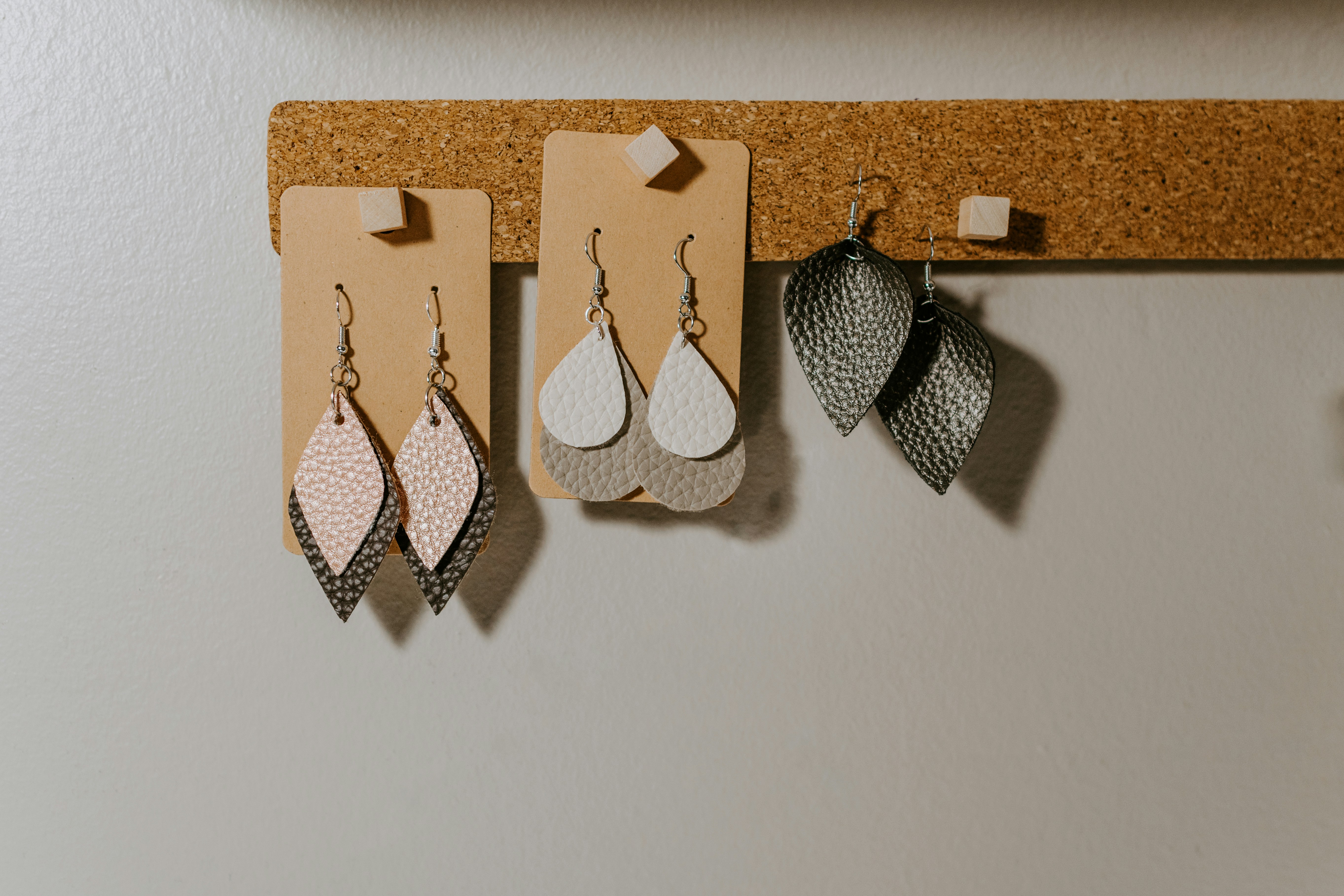 Leather earrings hanging together on a cork strip