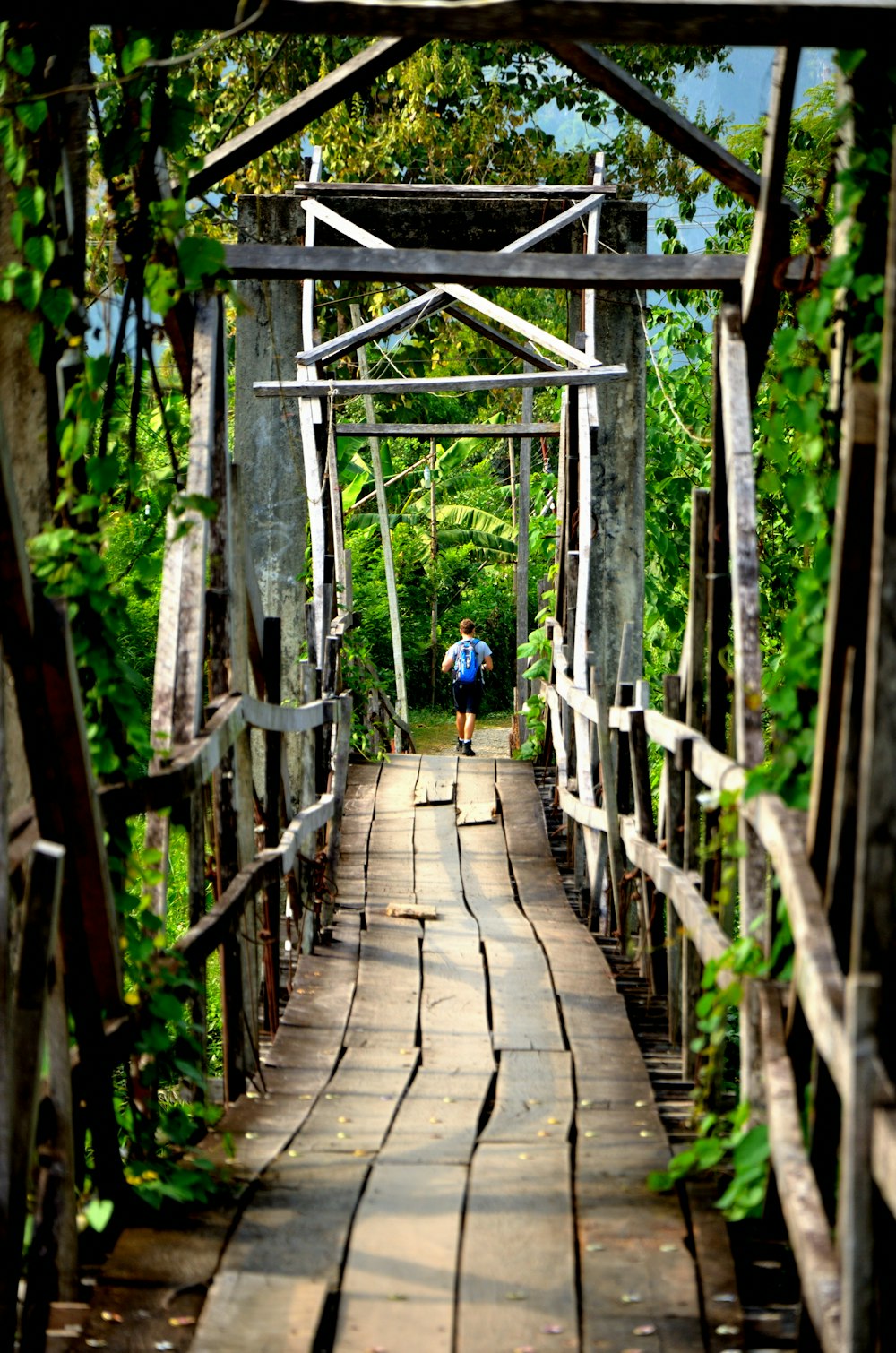 Persona che cammina sul ponte di legno marrone durante il giorno