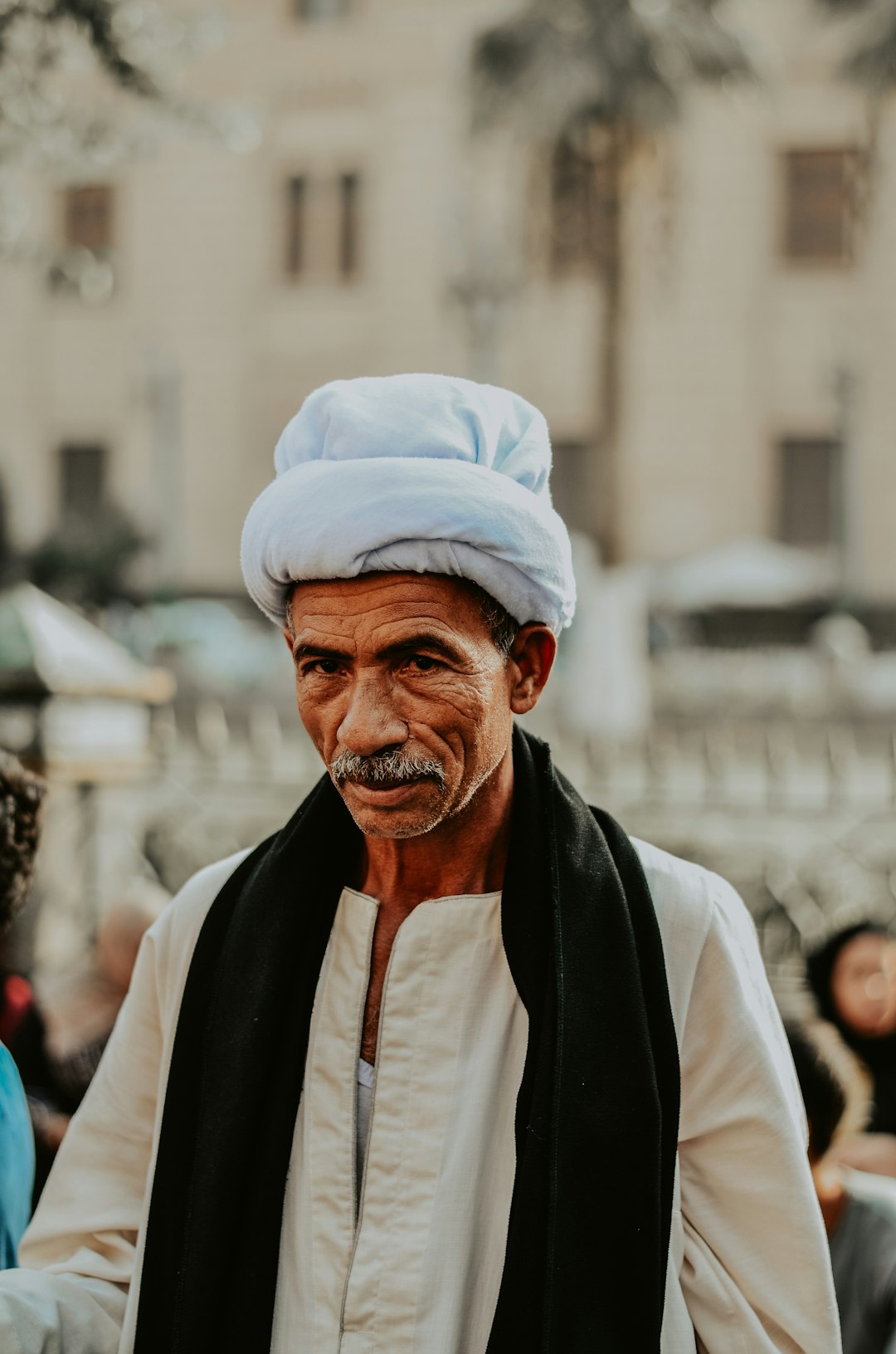 selective focus photography of man wearing gray headdress and black scarf during daytime