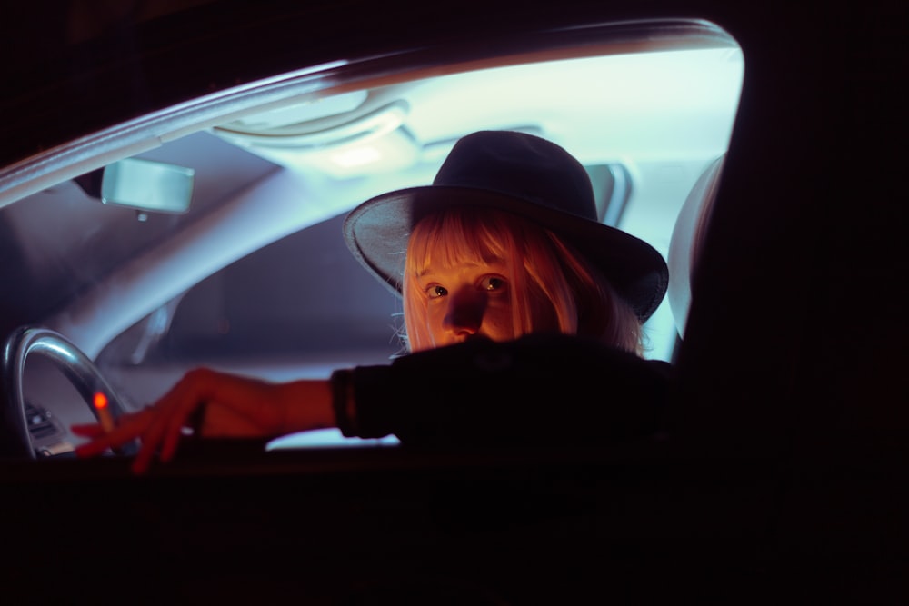 woman wearing black wide brim fedora hat riding car